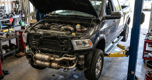 A Ram heavy-duty pickup on a workshop lift, hood up, 6.7-litre Cummins INLINE-SIX turbo diesel and the exhaust aftertreatment section both visible