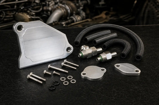 EGR delete kit components for 6.7 Powerstroke including billet block-off plates, coolant bypass fittings, and hardware on a workbench