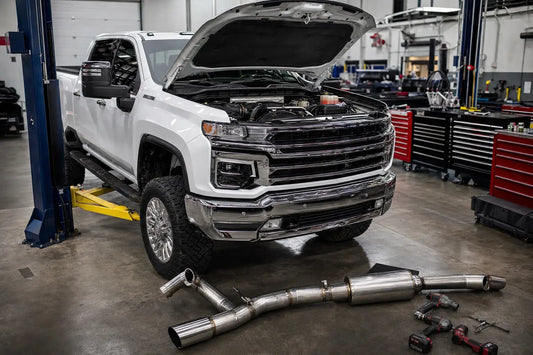 2017-2023 L5P Duramax full delete kit components laid out next to a Chevy Silverado HD in a performance diesel shop